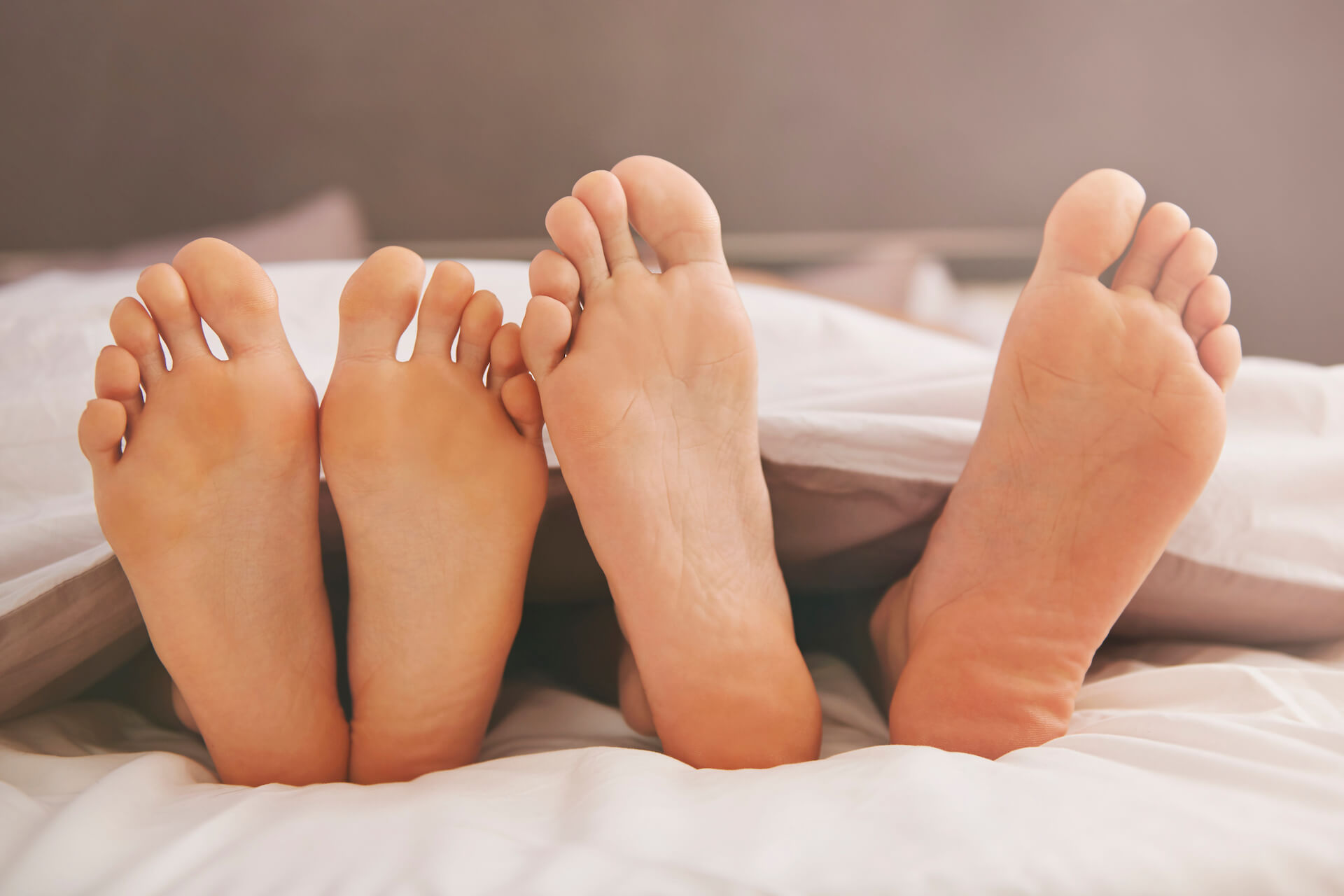Fußpaare im Bett