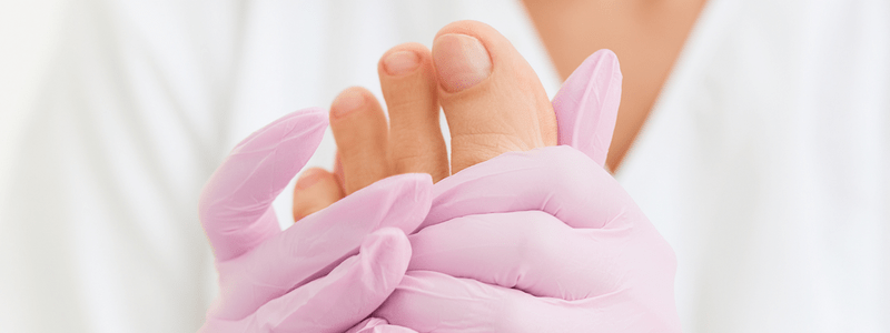 Ein Podologe oder eine medizinische Fußpflegekraft untersucht einen Fuß eines Diabetikers während einer regelmäßigen medizinischen Fußpflege-Sitzung